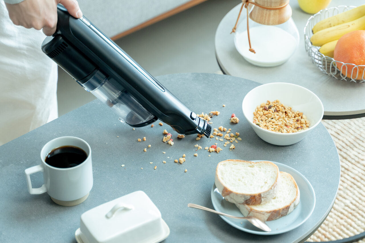 テーブルにこぼれた食べこぼしを、SH-J002をハンディ形態にして吸い取っているところ